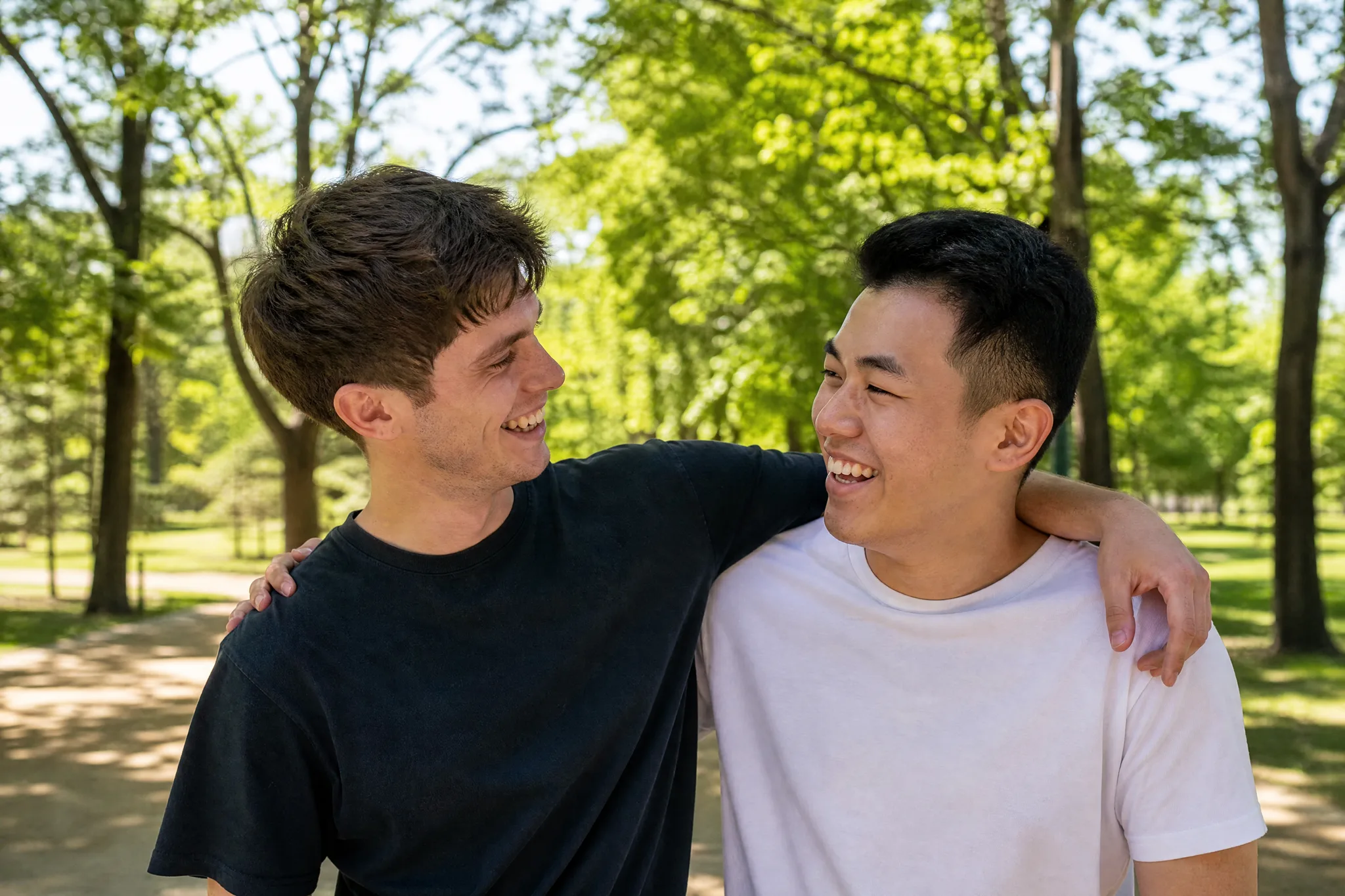 AI Hugging Video: The Smile After the Hug Two young men laughing with their arms around each other’s shoulders after a hug on a sunny path