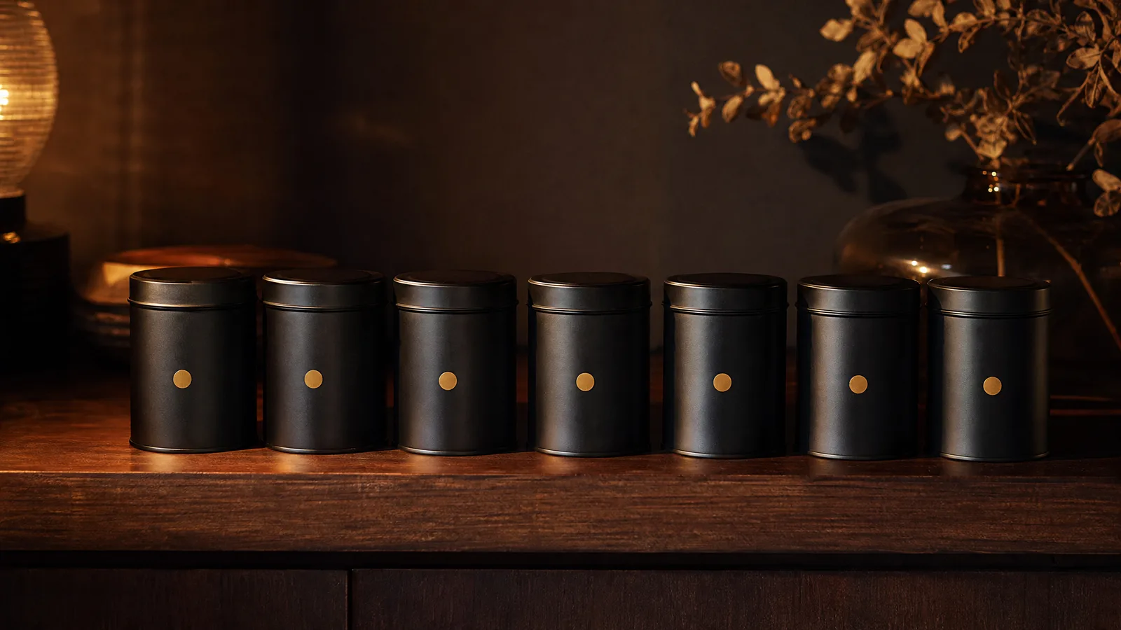 Seven unmarked black film canisters in a row on a walnut shelf, each with one small gold dot sticker