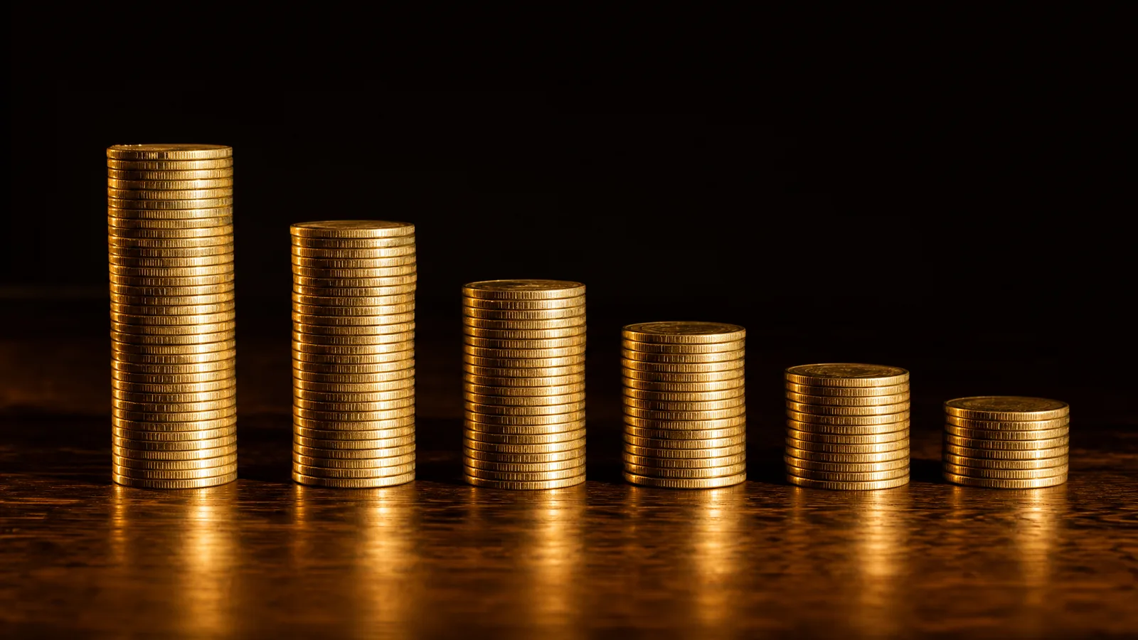 Six stacks of gold coins in a row on a walnut table, shrinking from tallest on the left to shortest on the right