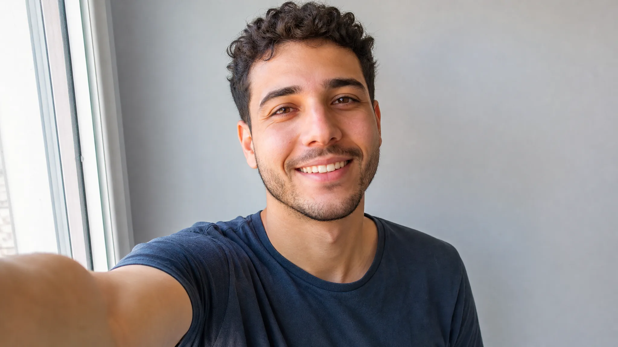 Bulin 47 AI Video Generator: From One Selfie Smiling man with short curly hair taking a clear front-facing selfie in soft daylight
