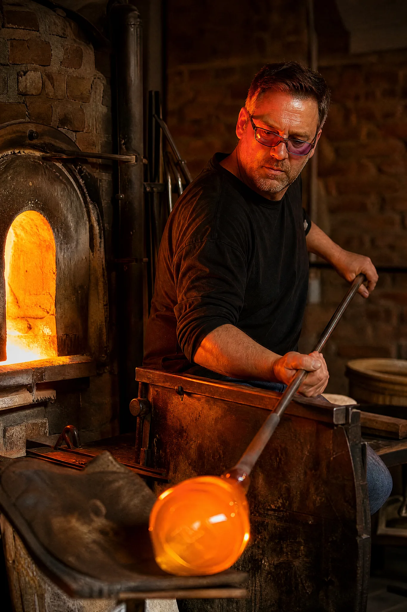 Grok Imagine Image 2: Light, Material and Viewpoint Glassblower turning glowing molten glass on a steel pipe beside a furnace