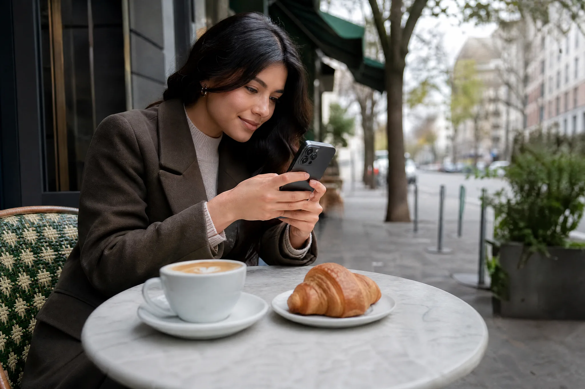 Image to Reel: A Photo for Your Next Instagram Post Content creator photographing a latte and croissant at an outdoor cafe table on an overcast morning