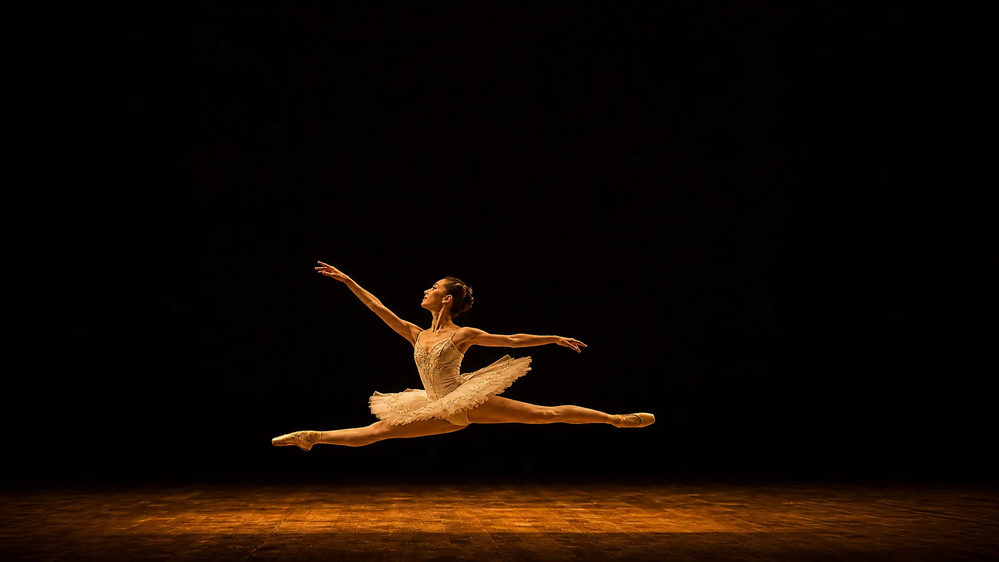 Ballerina mid-leap on a bare stage in the lower third with wide dark space above for a headline